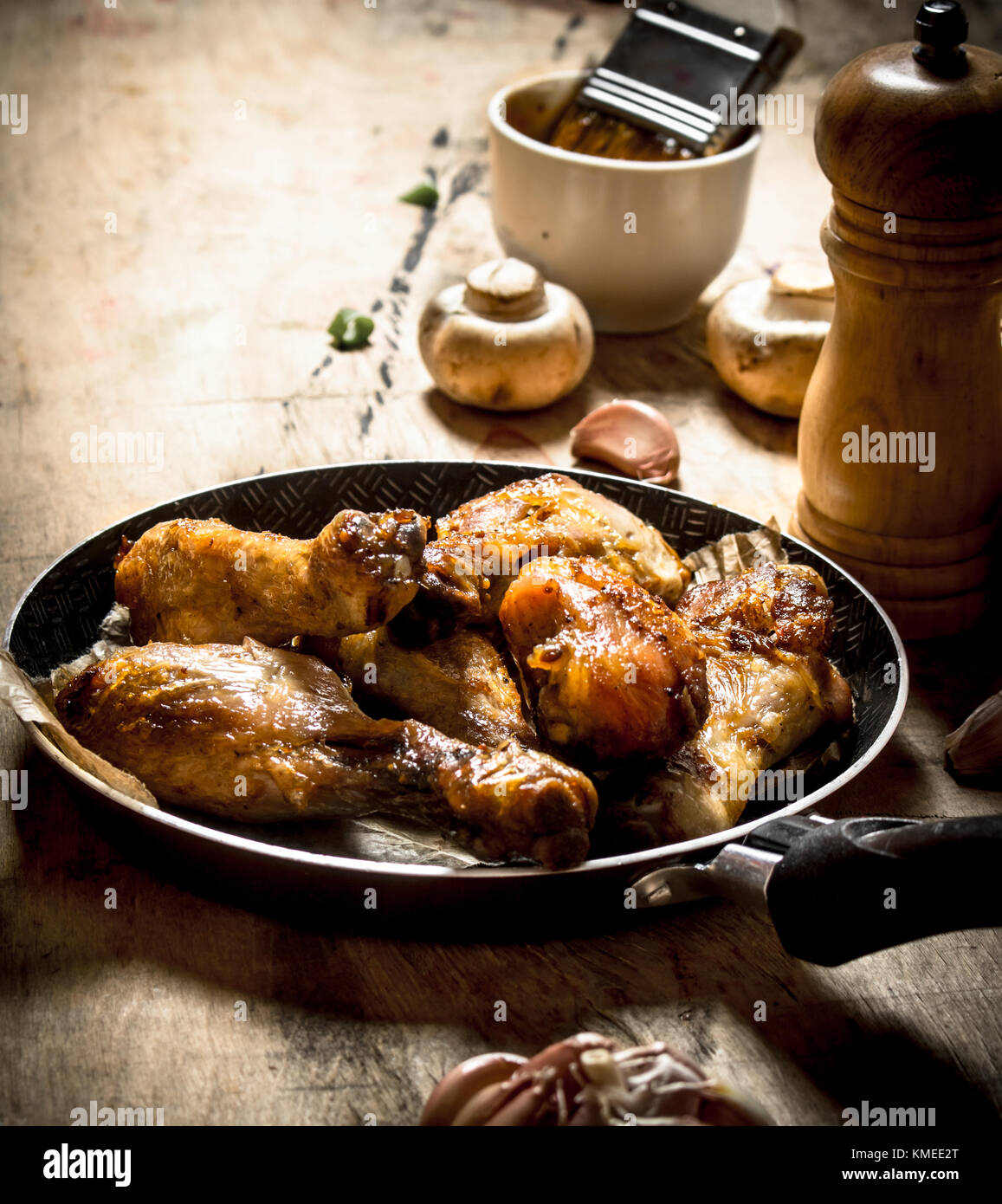 Fried Chicken Beine in einer Pfanne mit Tomaten, Pilze und Knoblauch. Stockfoto