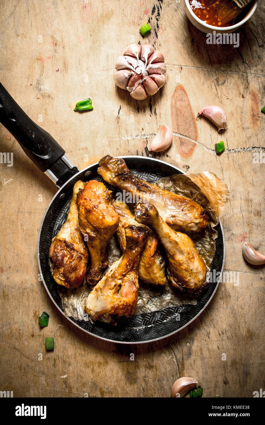 Würzige Hähnchenkeulen mit Knoblauch und Tomatensauce. Auf einem Holztisch. Stockfoto