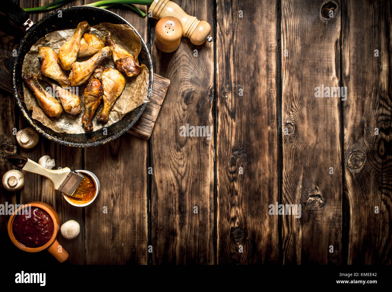 Gebratene Hähnchenschenkel mit Tomatensoße. Auf einem Holztisch. Stockfoto