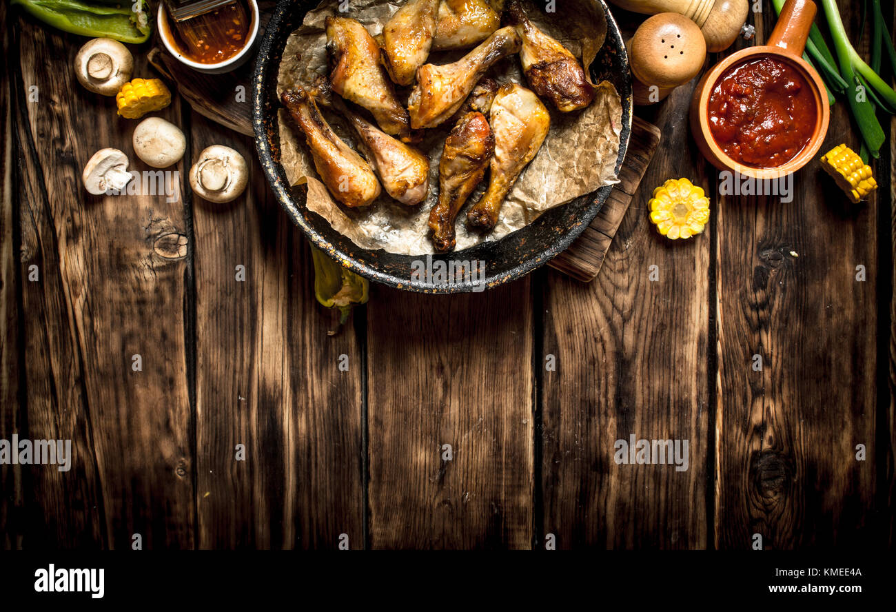Gebratene Hähnchenschenkel mit Tomatensoße. Auf einem Holztisch. Stockfoto