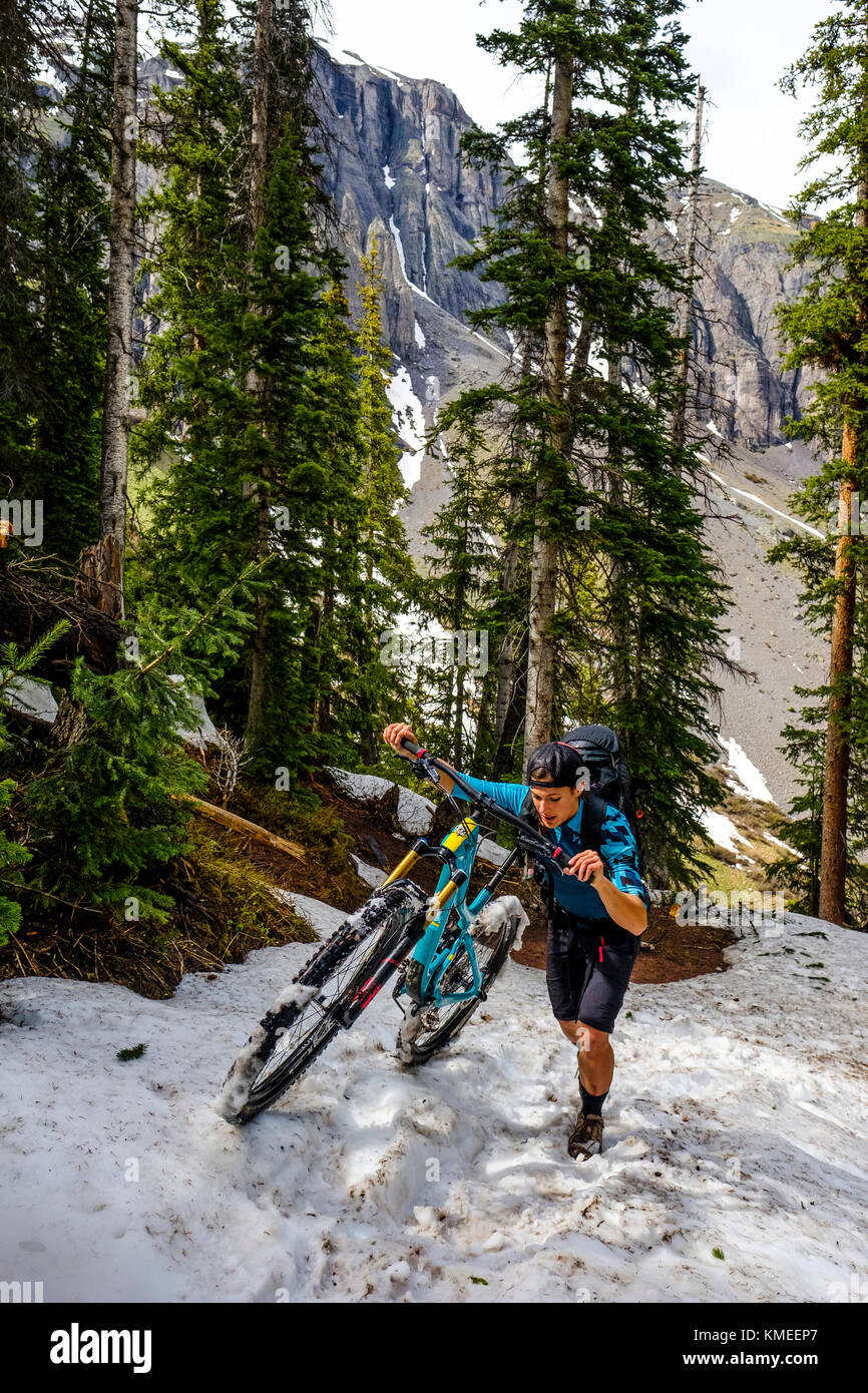 Weibliche Mountainbiker in der malerischen Landschaft schiebt Bike wenn Schnee auf dem Eis Trail Seen, USA Stockfoto