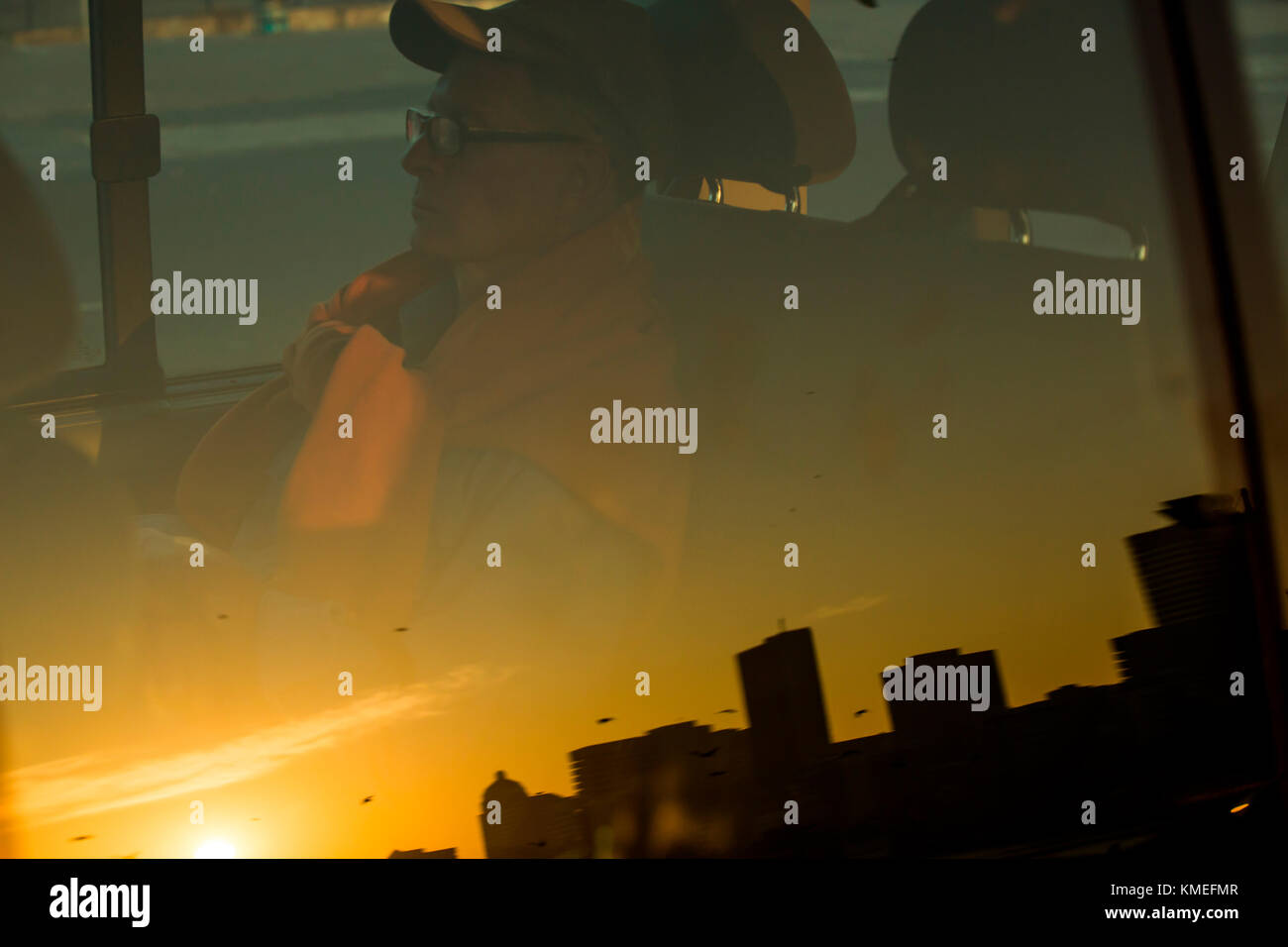 Spiegelung des Mannes, der im Auto im Fenster und in der Skyline sitzt Der Stadt bei Sonnenuntergang, Durban, kwazulu-Natal, Südafrika Stockfoto