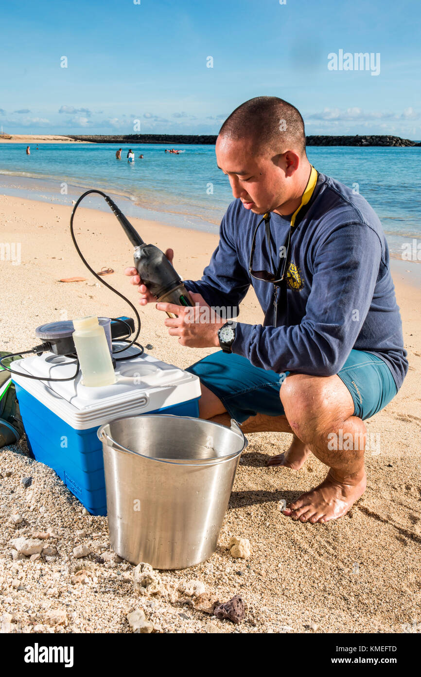 Wataru Kumagai vom State of Hawaii Department of Health Clean Water Branch, zeigt Wasserprobennahmen an hawaiianischen Stränden am Ala Moana Beach in Honolulu mit Instrumenten wie einem Trübungsmessgerät.für den vollen Umfang der Messungen, Laborarbeiten wurden extern durchgeführt. Stockfoto