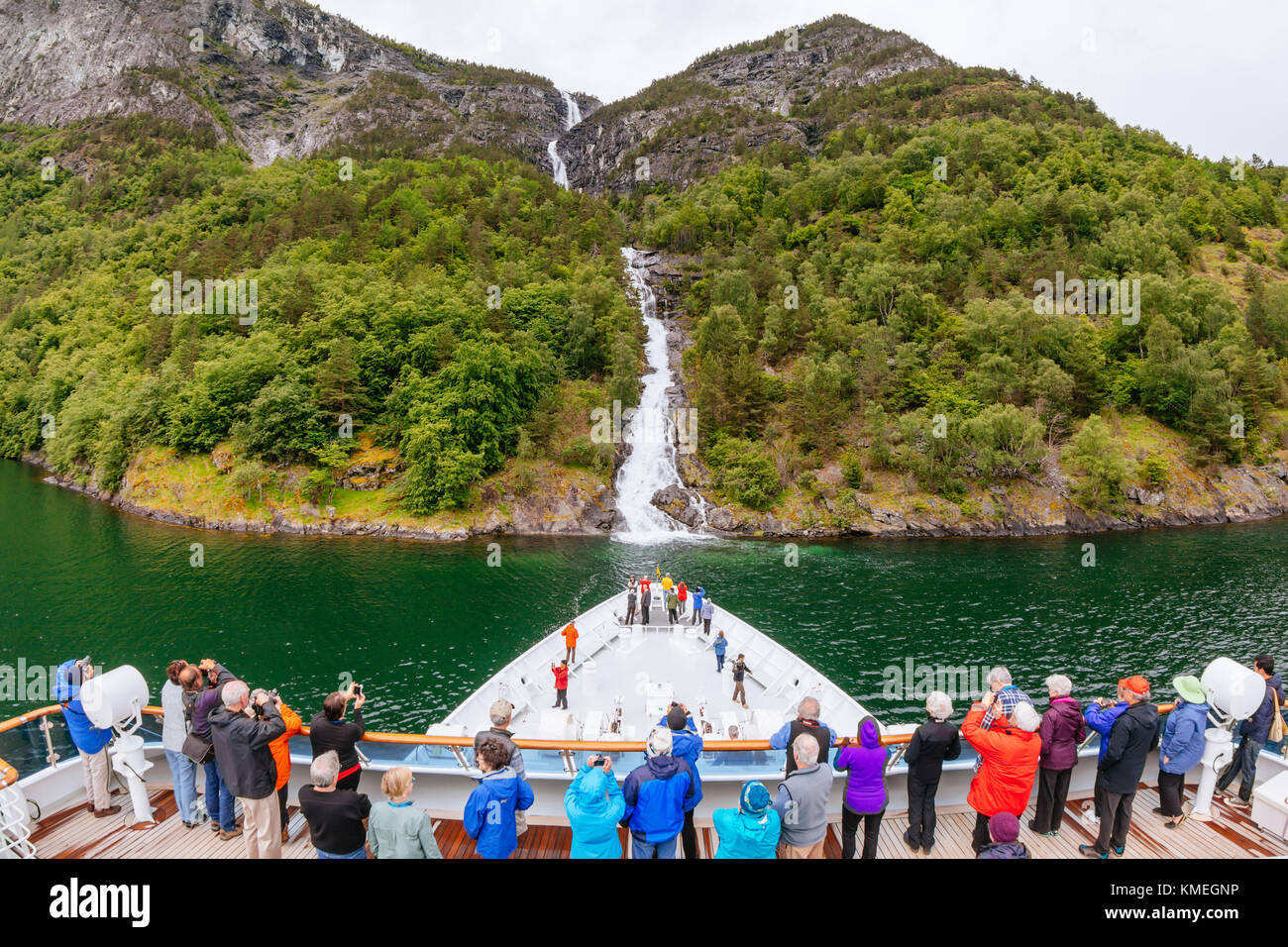 Große Gruppe von Passagieren auf dem Schiff Blick auf Sicht und Fotografieren des Wasserfalls am Naeroyfjord, Sogn Og Fjordane, Norwegen Stockfoto