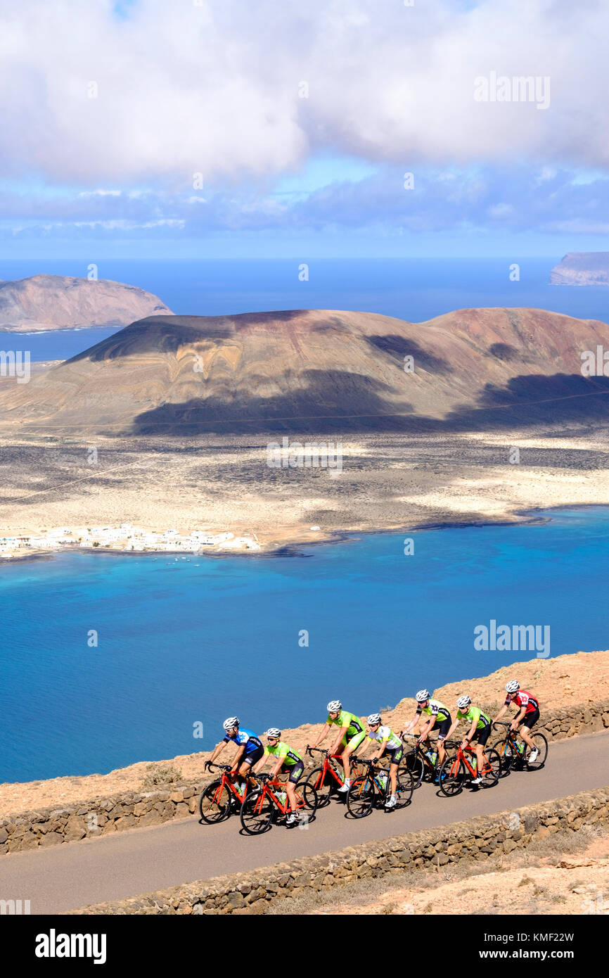Gruppe von Radfahrern radeln auf der Küstenstraße, Nationalpark Timanfaya auf Lanzarote, Kanarische Inseln, Spanien Stockfoto