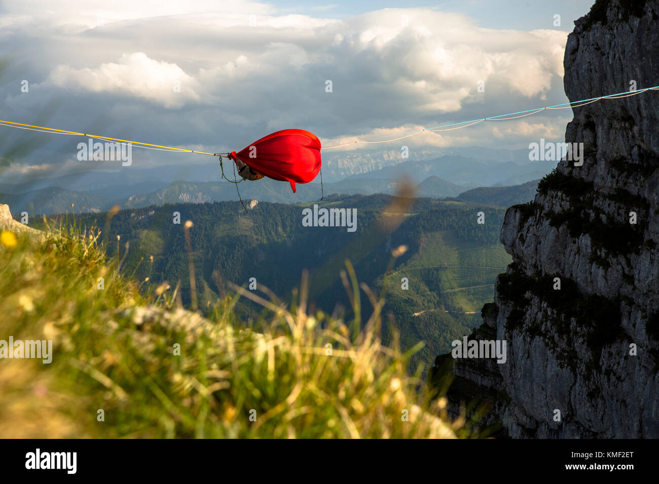 Person, die in der Hängematte schläft und auf Linie über Bergen hängt In Niederösterreich, Österreich Stockfoto
