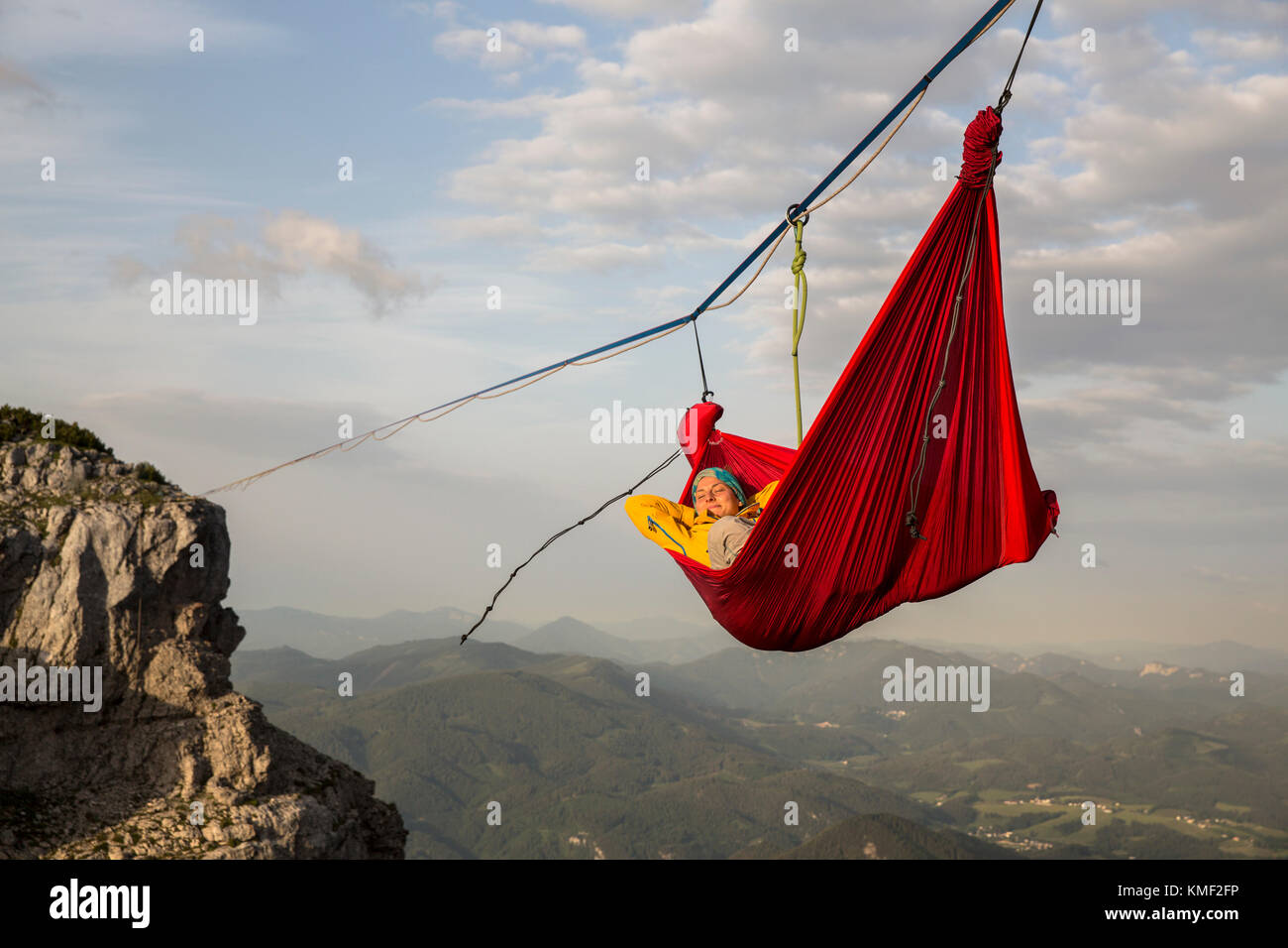 Person, die in der Hängematte schläft und auf Linie über Bergen hängt In Niederösterreich, Österreich Stockfoto