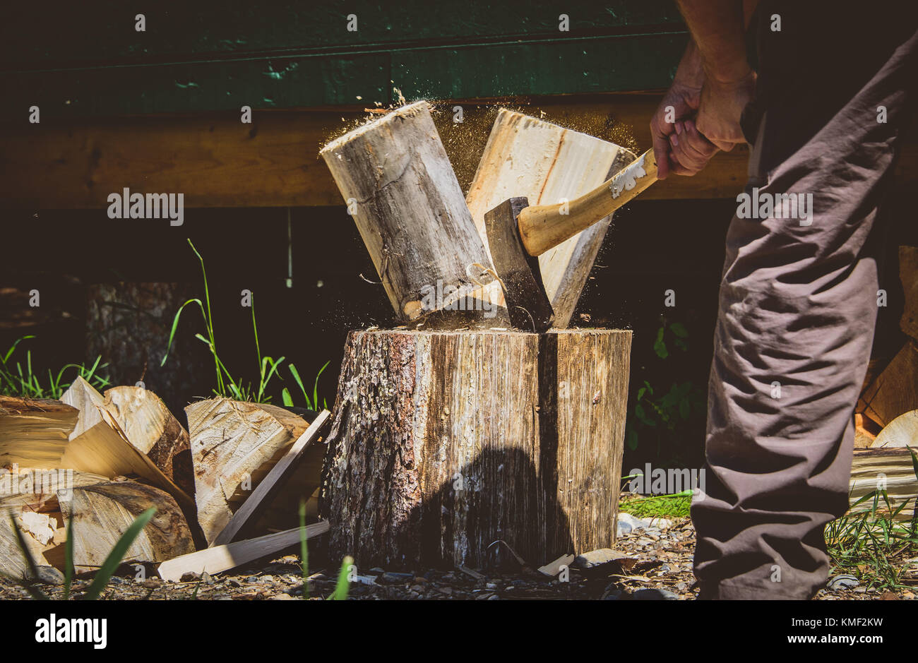 Spalten von Holz mit einer Axt im Freien im Sommer Stockfoto