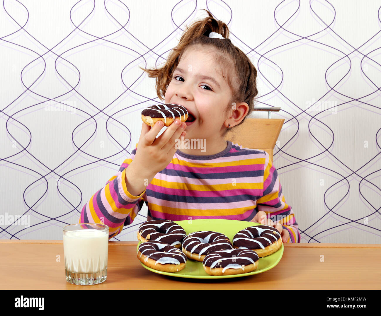 Kleines Mädchen essen Schokolade Donuts Stockfoto