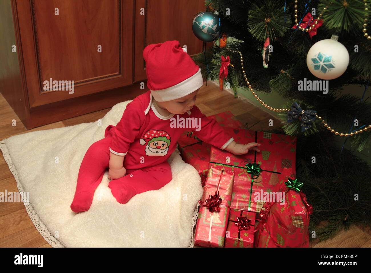 Glücklich süße kleine Baby in Santa Kostüm in der Nähe von Xmas Tree dekorieren. Stockfoto