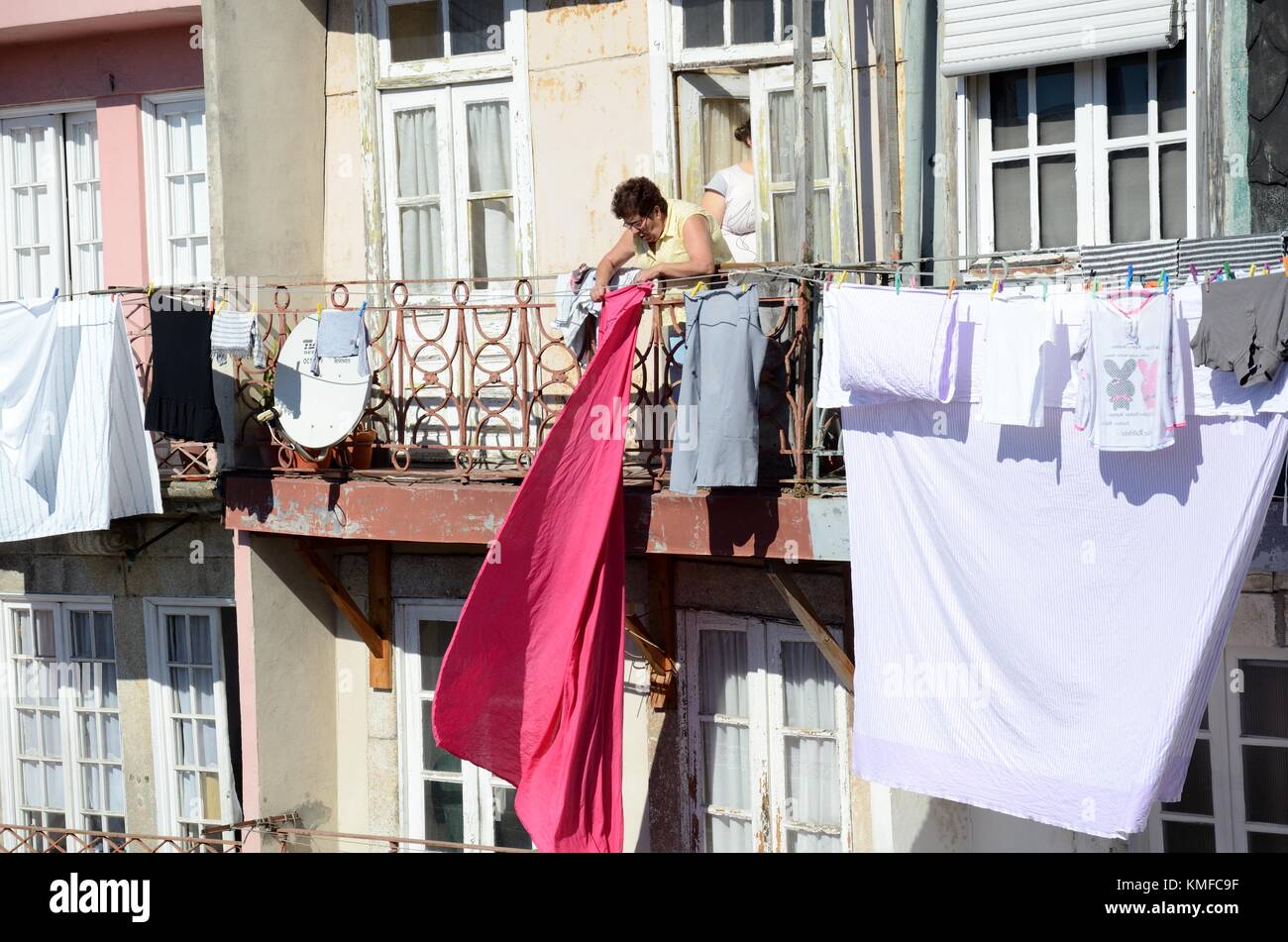 Eine Frau hängenden Waschen, auf einem Balkon eines alten Stadthaus Porto Portugal zu trocknen Stockfoto