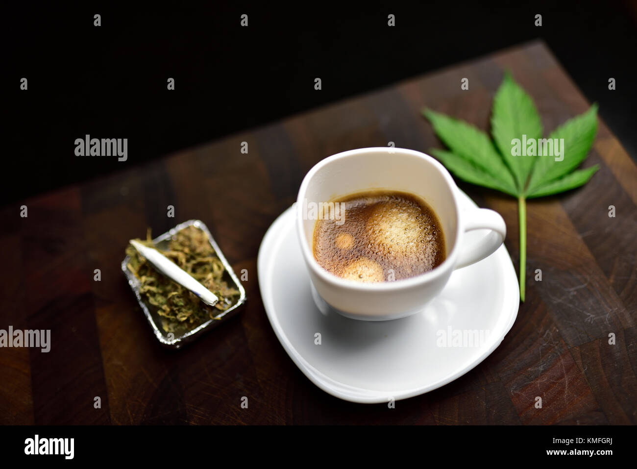 Weiß Kaffeetasse auf hölzernen Metzger Schneidbrett mit Gelenk, Cannabis Bud und Cannabis Blatt Stockfoto