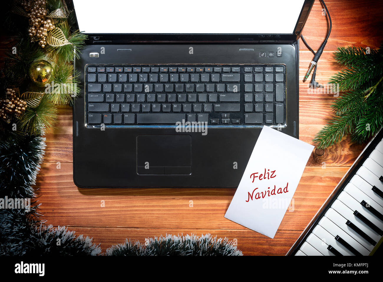 Feliz Navidad - musikalische Weihnachten Hintergrund mit musikalischen Tastatur, Laptop auf einem Holztisch Stockfoto