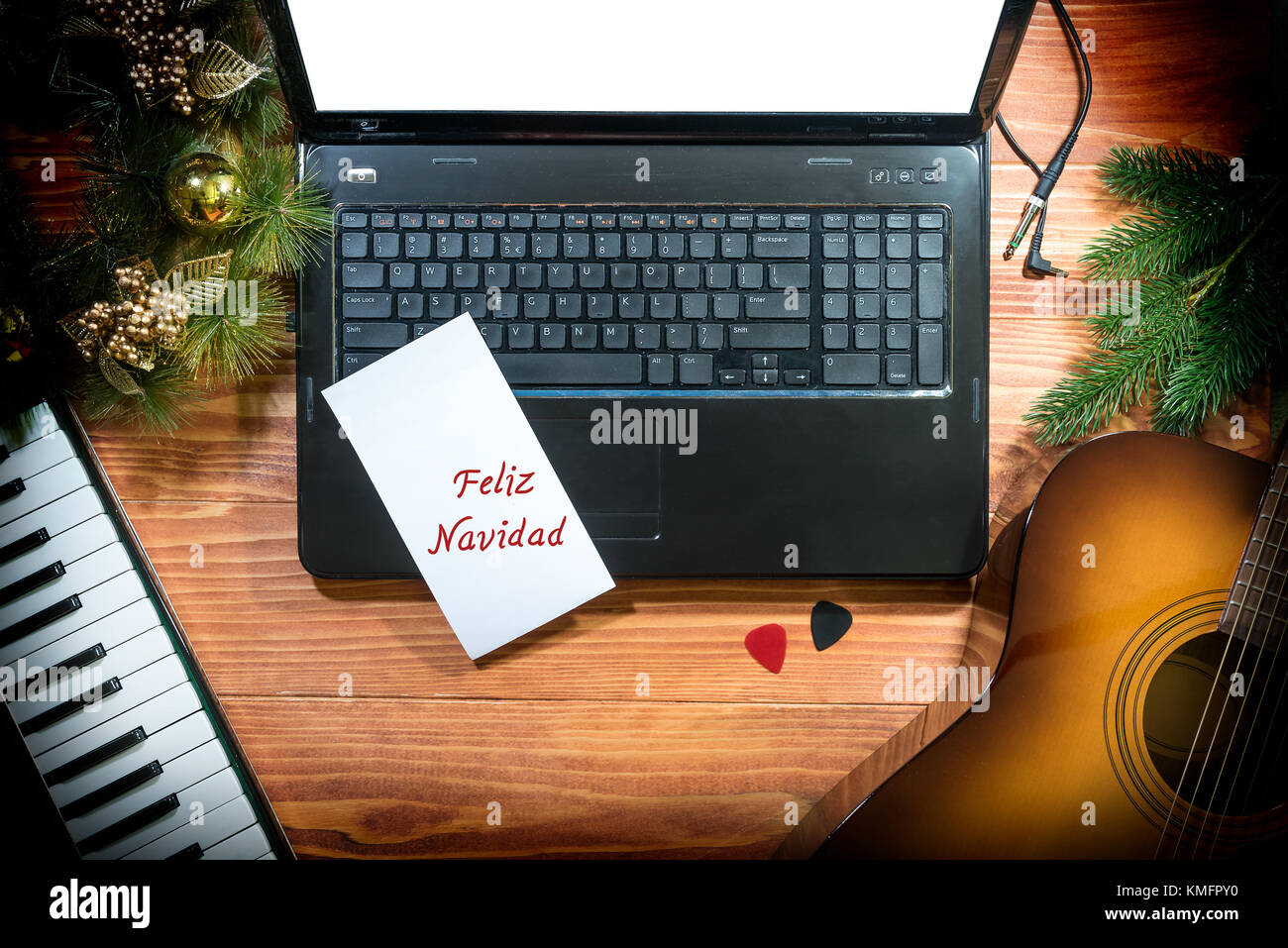 Feliz Navidad - musikalische Weihnachten Hintergrund mit akustischer Gitarre, Keyboard, Laptop auf einem Holztisch Stockfoto