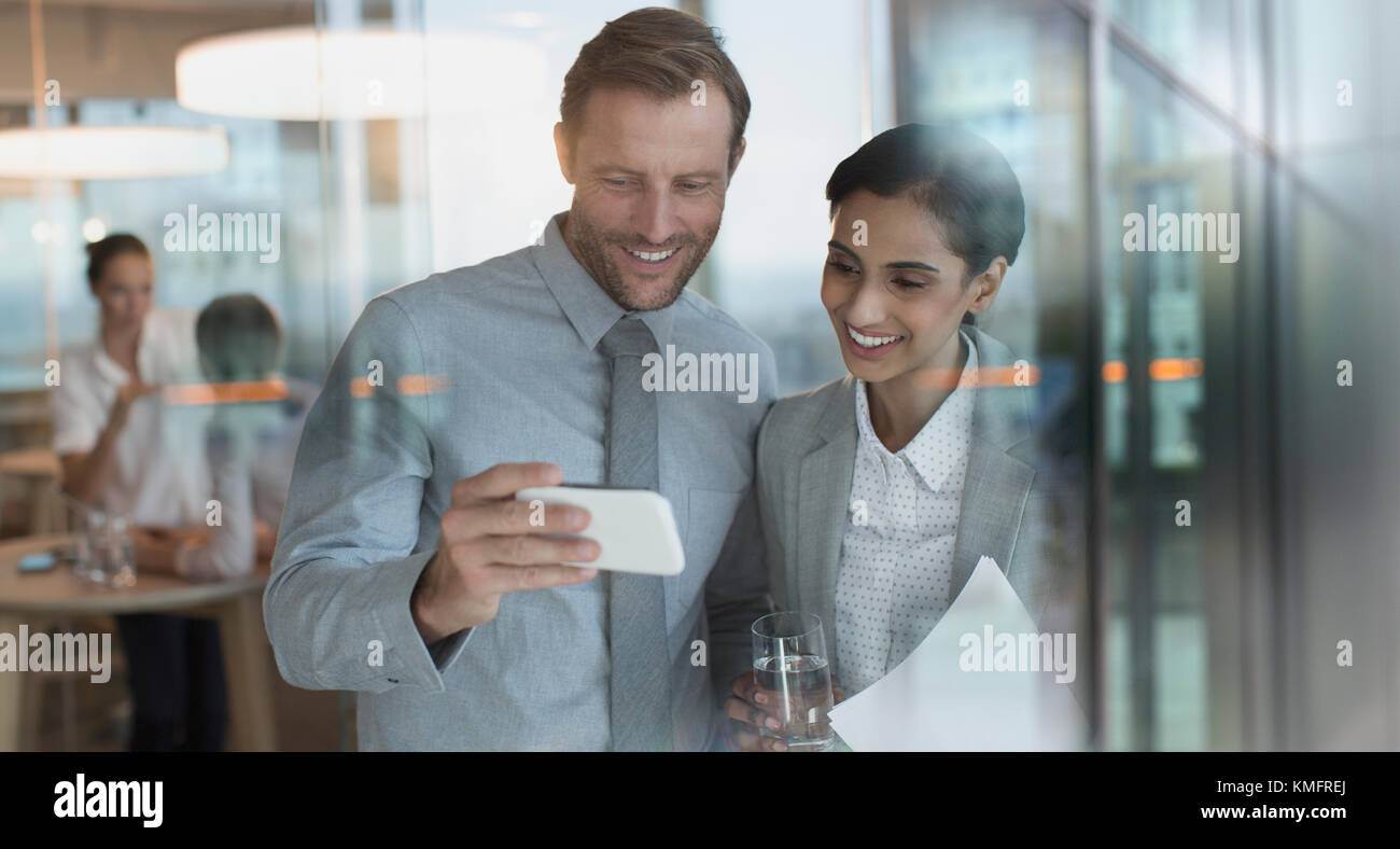 Lächelnd Geschäftsmann und Geschäftsfrau Video auf Smart Phone im Büro Stockfoto