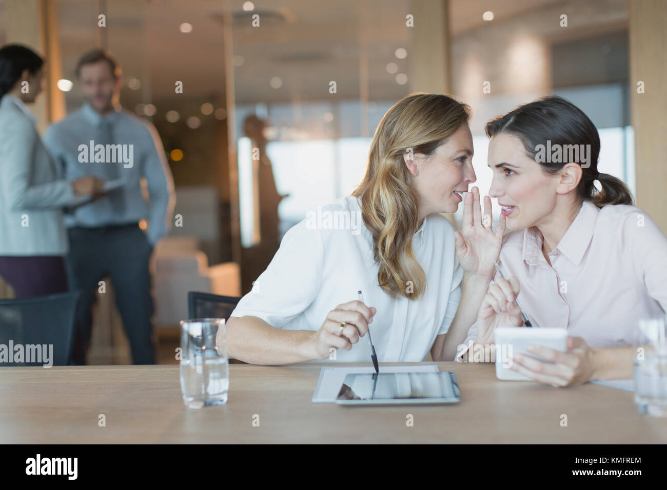 Geschäftsfrauen mit digitalen Tablets flüstern in Konferenzräumen Stockfoto