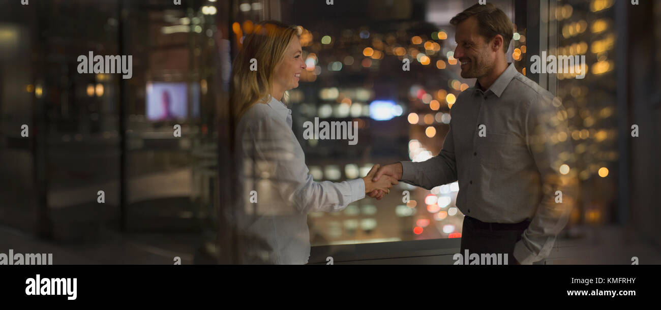 Geschäftsmann und Geschäftsfrau Handshake im Büro in der Nacht Stockfoto