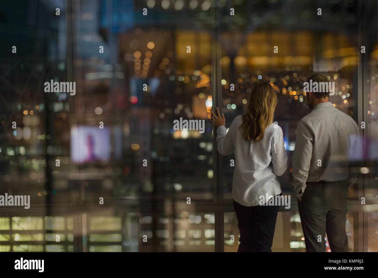 Kaufmann und Kauffrau aus städtischen Büro Fenster bei Nacht Stockfoto