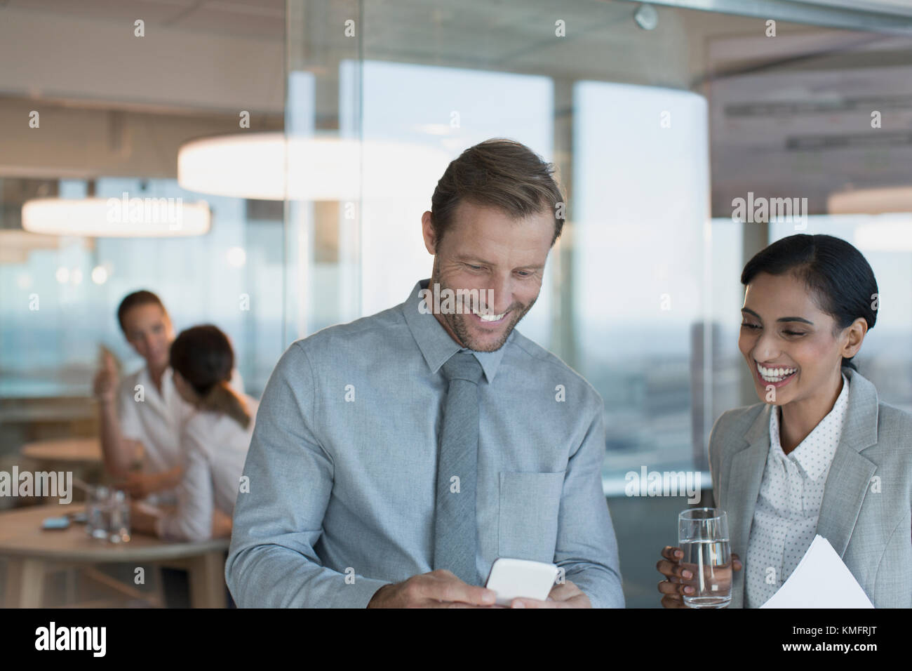 Kaufmann und Kauffrau mit Handy im Büro Stockfoto