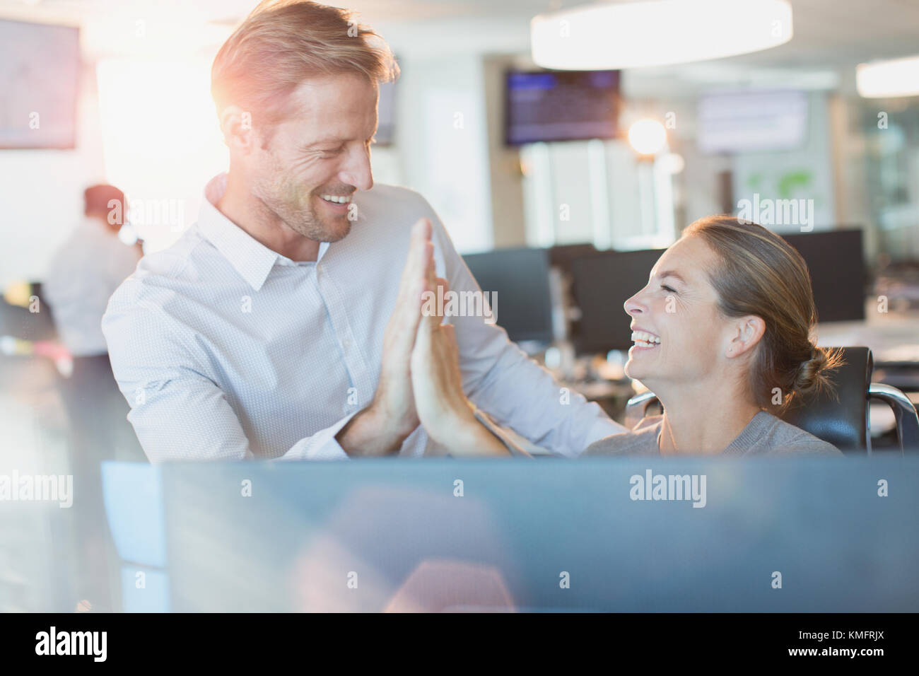 Geschäftsmann und Geschäftsfrau High-Fiving am Computer im Büro Stockfoto