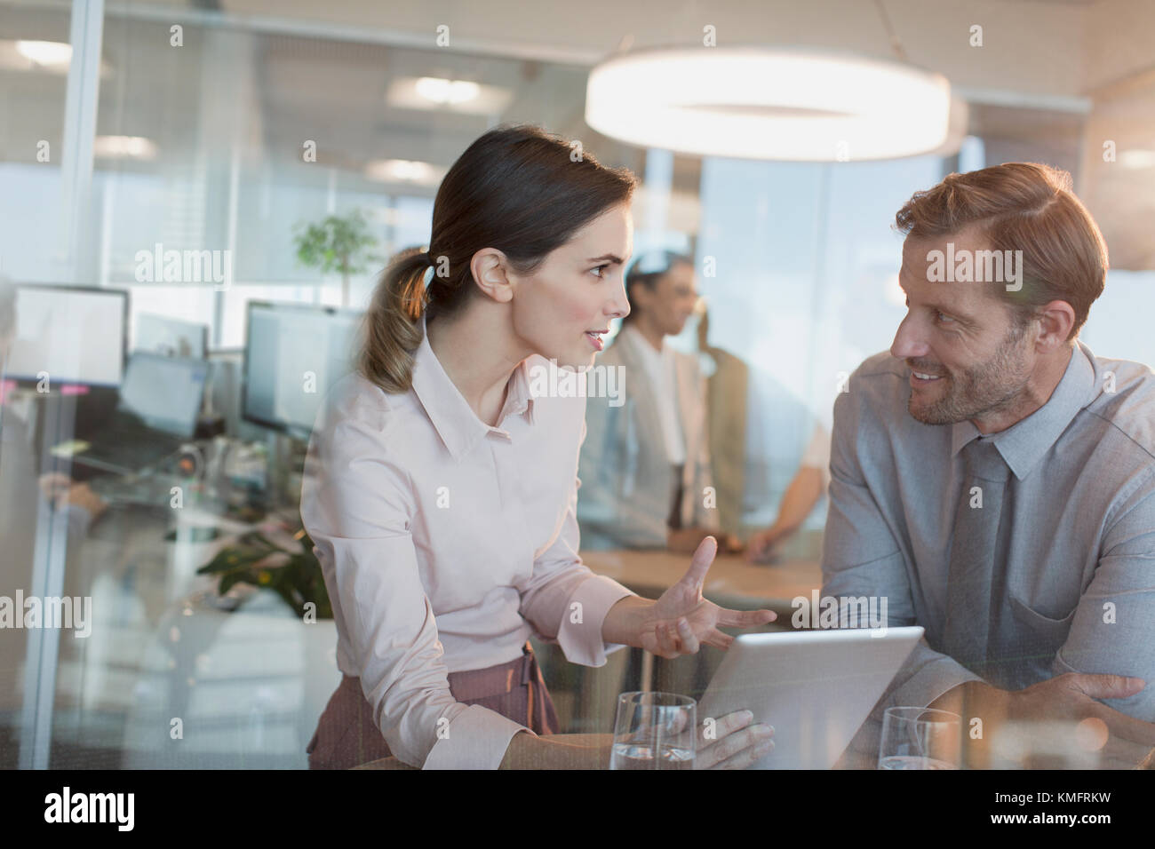 Geschäftsfrau mit digitalem Tablet erklärt Geschäftsleuten in Büromeeting Stockfoto
