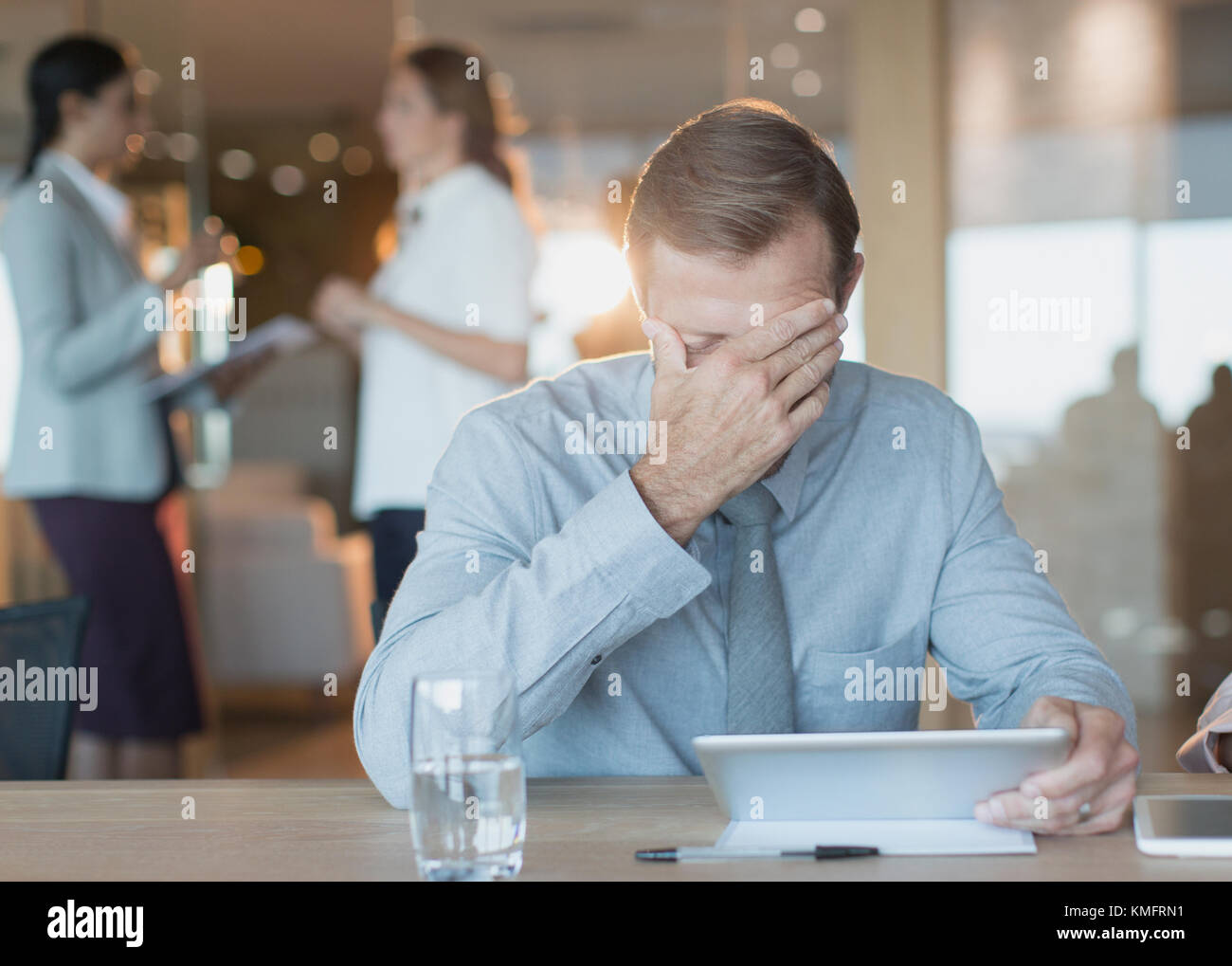 Müde, gestresste Geschäftsmann mit digitalen Tablet in Konferenzraum Stockfoto