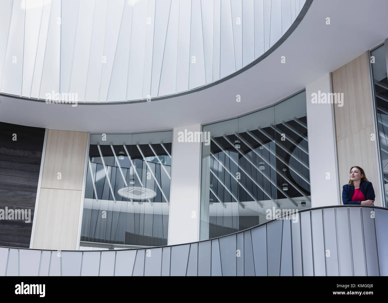 Nachdenkliche Geschäftsfrau, die auf einem architektonischen, modernen Bürobalkon steht Stockfoto