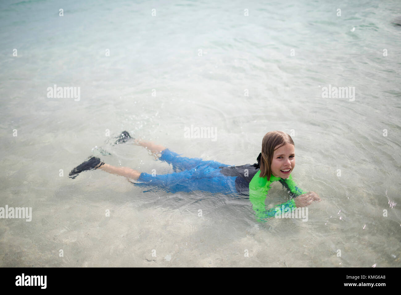 Porträt eines Mädchens im Neoprenanzug, das auf dem Wasser schwimmt Stockfoto