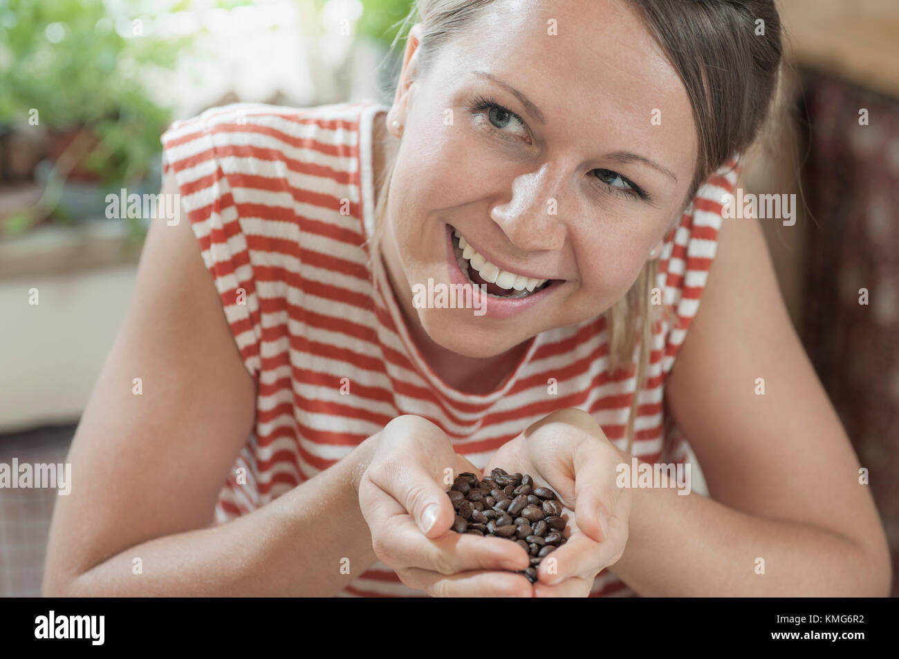 Junge Frau mit Handvoll geröstete Kaffeebohnen Stockfoto