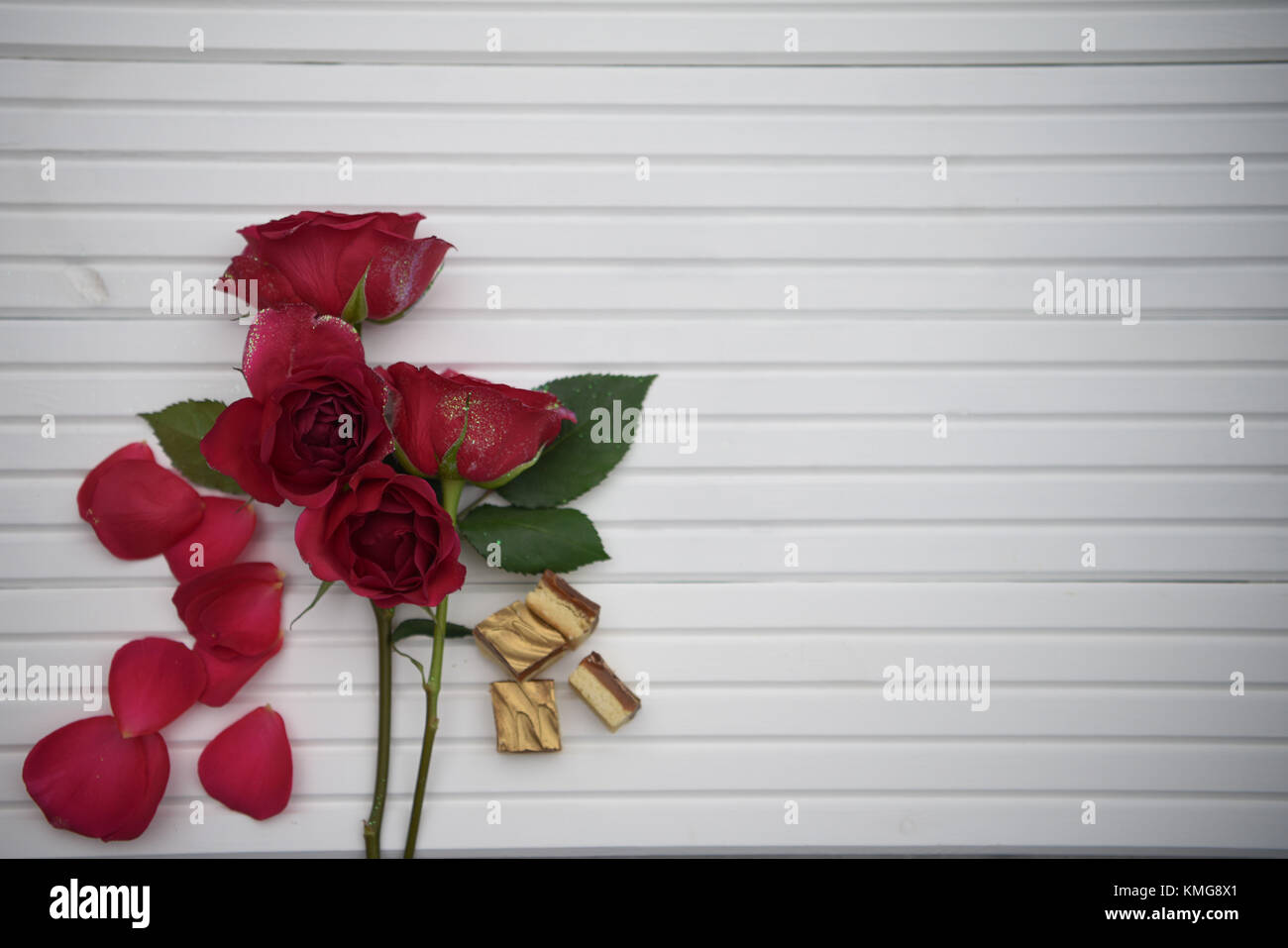Romantische fotografie Bild mit frischen echten roten Rosen Blumen und edle Pralinen auf weißem Holz Hintergrund mit Kopie Raum ideal für den Valentinstag Stockfoto