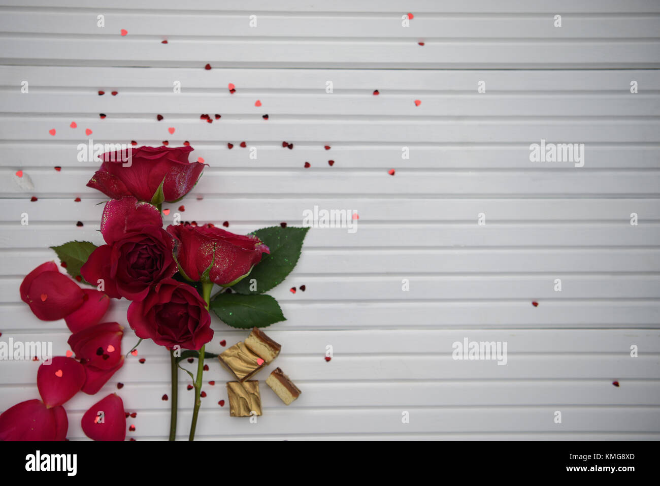 Romantische fotografie Bild mit frischen echten roten Rosen Blumen und edle Pralinen auf weißem Holz Hintergrund mit Kopie Raum ideal für den Valentinstag Stockfoto