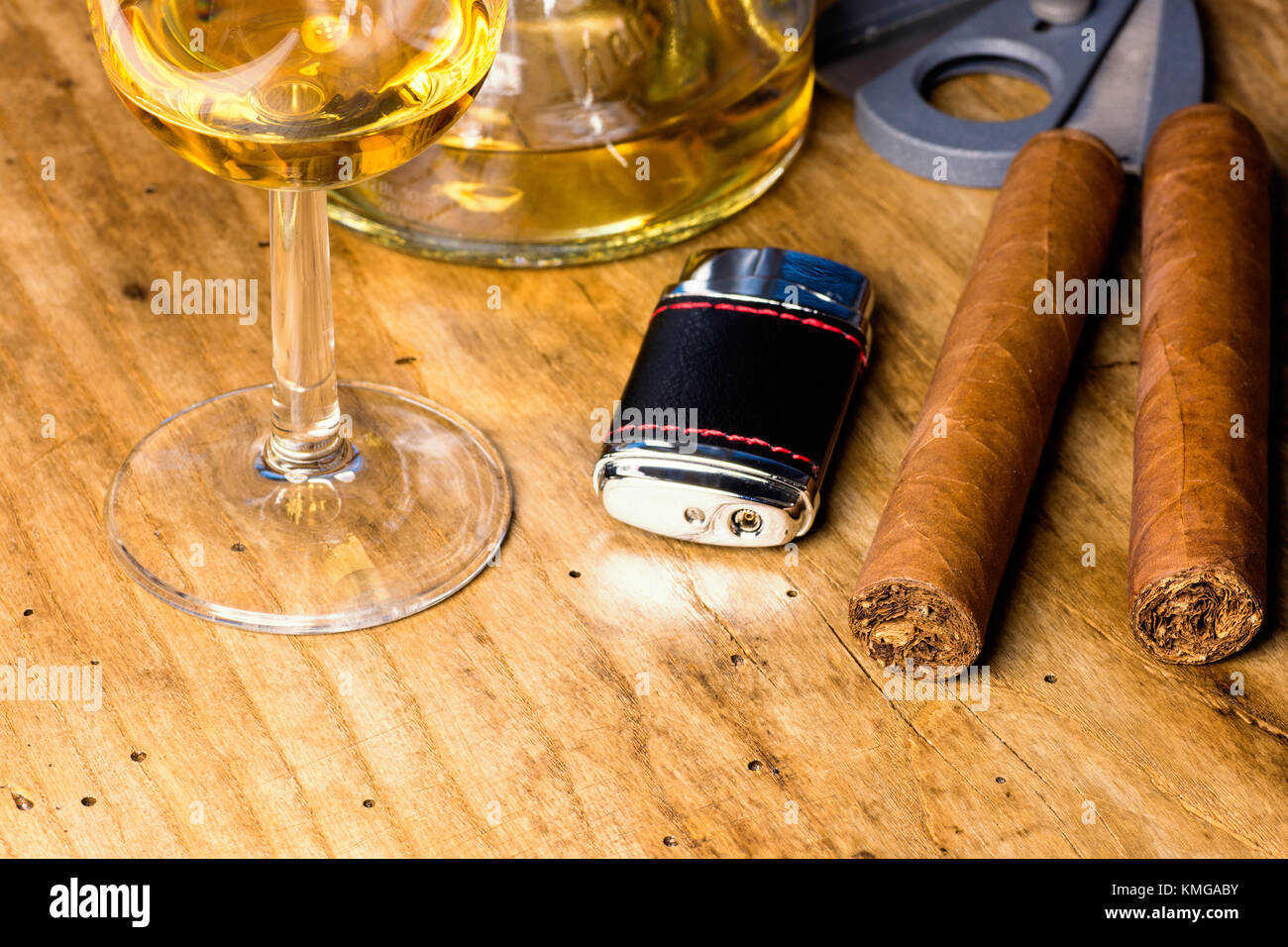 Zigarre mit Flasche und Whiskey Glas, leichter und Zigarrenabschneider auf einem alten Holz- Board Stockfoto