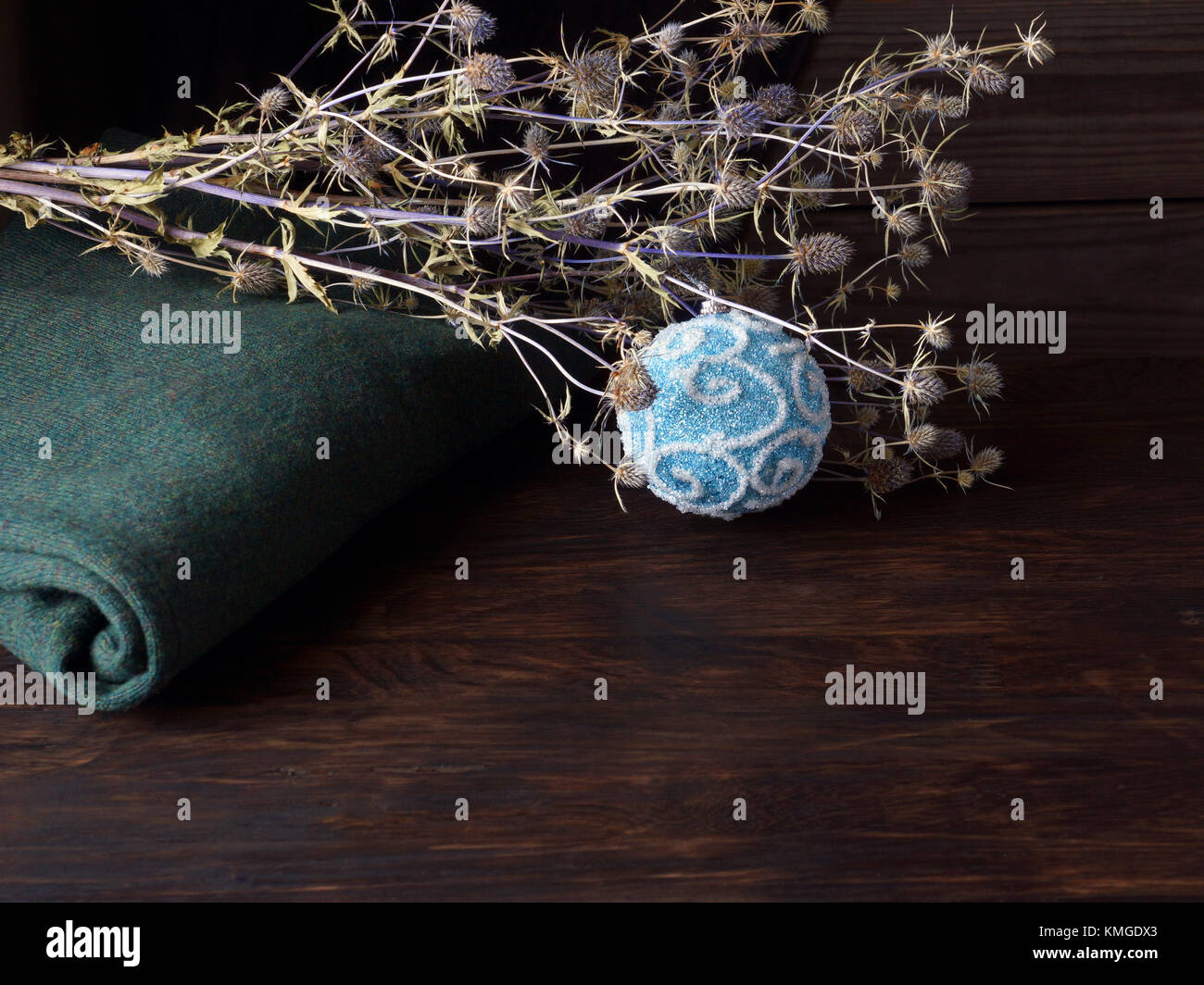 Einen warmen grünen Pullover, getrocknete Blumen und eine blue christmas ball liegen auf der Eiche Tisch. Stockfoto