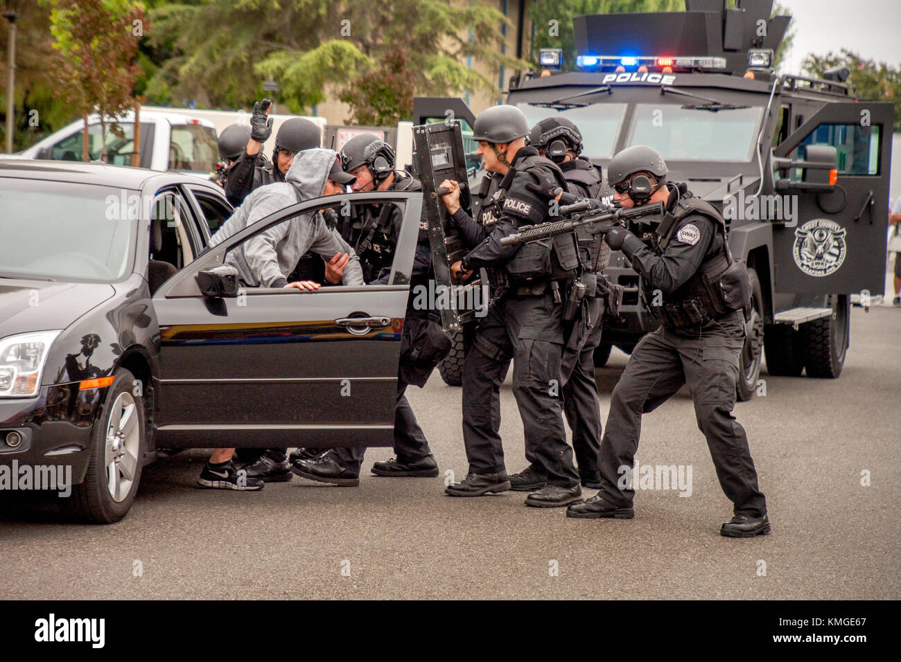 Ein freiwilliger Täter stellt sich der Polizei swat (spezielle Waffen und Taktiken) Team während einer Demonstration in Fountain Valley, CA. Im Hintergrund ist das Team der Bär Katze gepanzertes Fahrzeug. Stockfoto