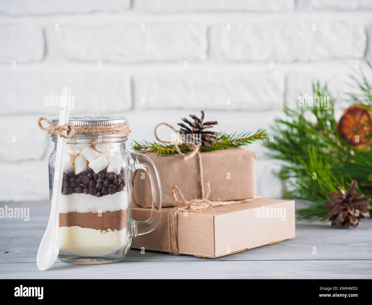 Heiße Schokolade Mix im Marmeladenglas und rustikalen Geschenkboxen auf grau Tabelle und weiße Wand. Weihnachten und Winter Urlaub budget-freundliche Geschenke Idee. Kopieren Stockfoto