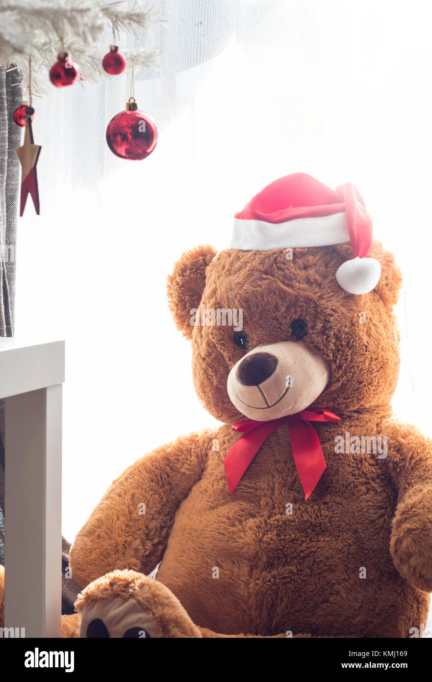 Teddybär Spielzeug mit rote Weihnachtsmütze sitzen unter Christbaumschmuck Stockfoto