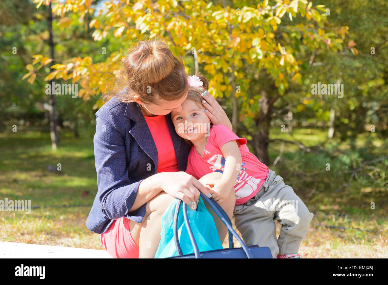 Gebiet Wolgograd, Russland vom 6. Oktober 2016. Eine junge Mutter sitzt auf der Kante der bürgersteig und umarmt ihre Kind, lächelt. Stockfoto