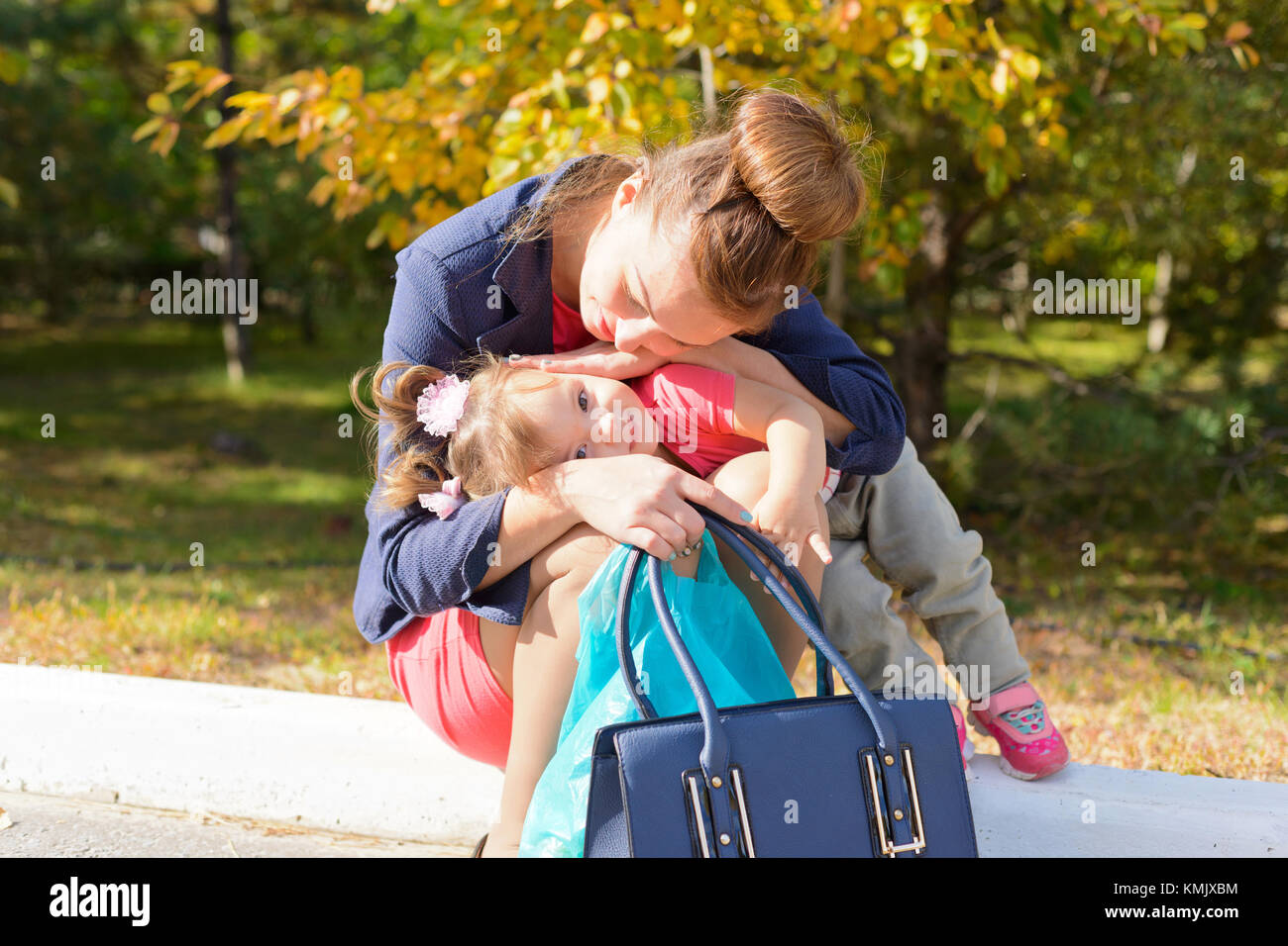 Gebiet Wolgograd, Russland vom 6. Oktober 2016. Eine junge Mutter sitzt auf der Kante der bürgersteig und umarmt ihre Kind, lächelt. Stockfoto