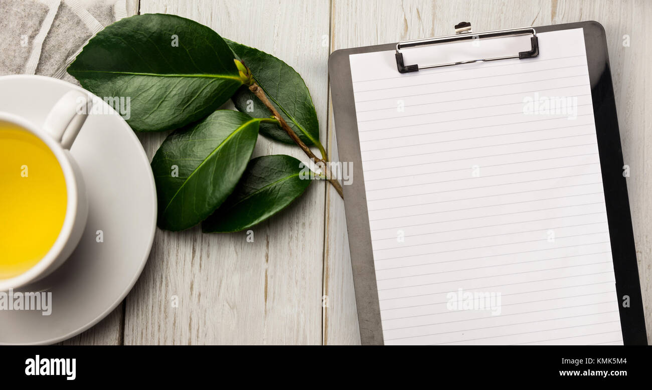 Schwarz notepad gegen Tasse Kräutertee am Tisch Stockfoto