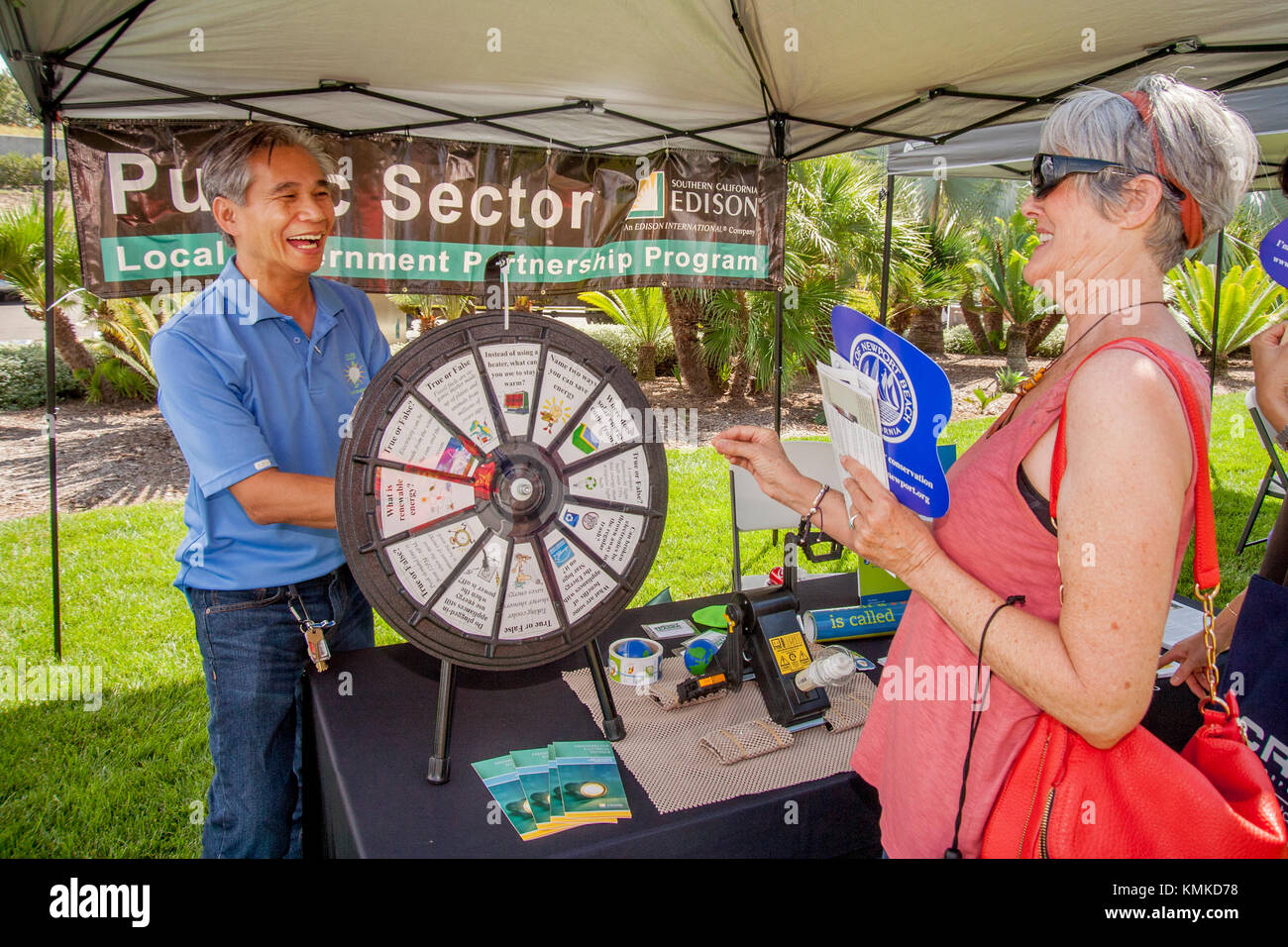 An einem Versorgungsunternehmen im öffentlichen Sektor kommunale Partnerschaft Programm stand eine asiatische amerikanische Demonstrator Spins ein 'Rad' Frage von richtig oder falsch Energie - Verwandte Themen während einer ökologischen Street Fair in Newport Beach, CA. Stockfoto