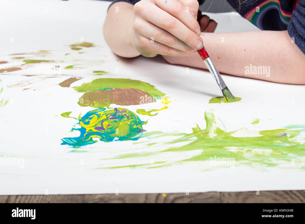 Junge Kind spielt mit Pinsel im splattered Farbe auf weißem Hintergrund Stockfoto