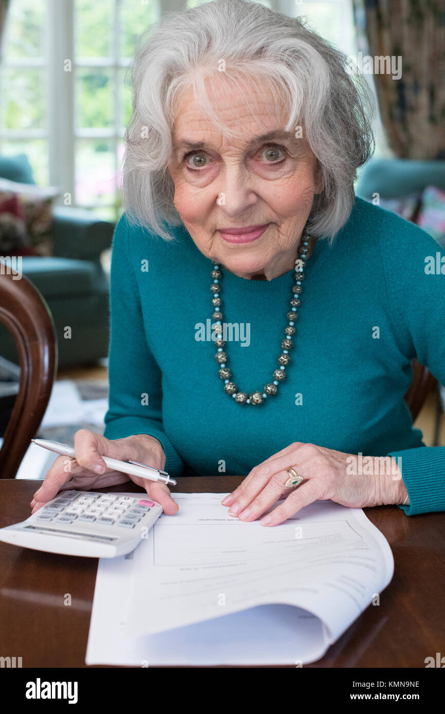 Lächelnd Senior Frau durch Rechnungen zu Hause gehen Stockfoto