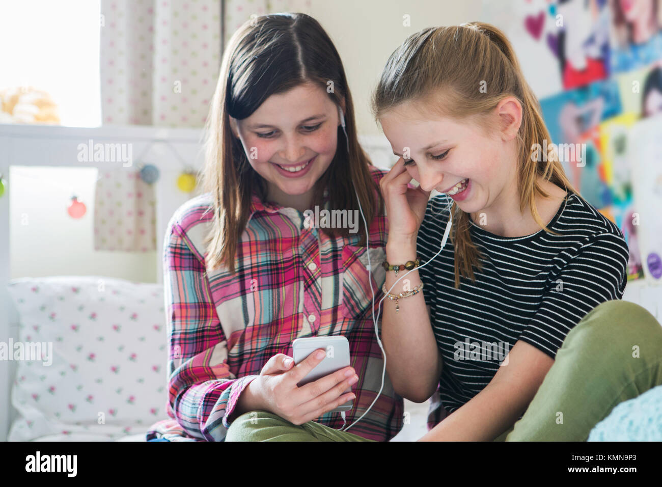 Zwei Mädchen Streaming Musik vom Mobiltelefon im Schlafzimmer Stockfoto