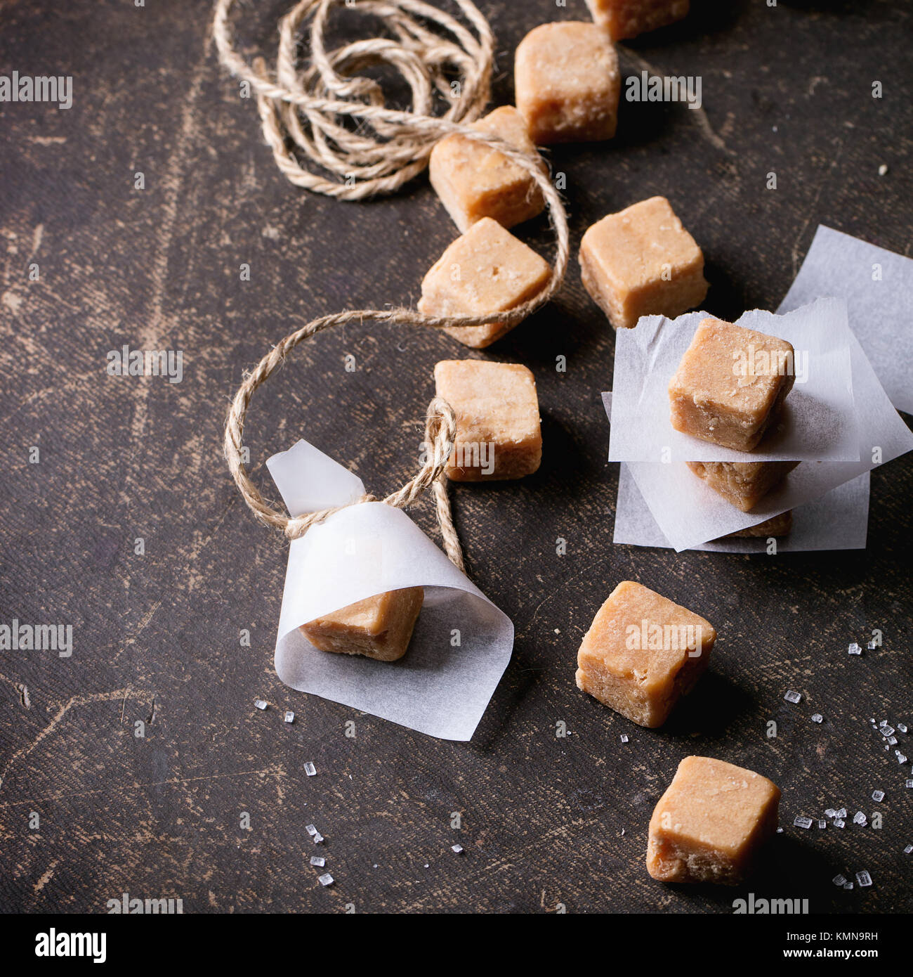 Fudge, Süßigkeiten und Karamell auf Backpapier, serviert mit Gewinde auf dunklem Hintergrund. Ansicht von oben. Tiefenschärfe, quadratisches Bild Stockfoto