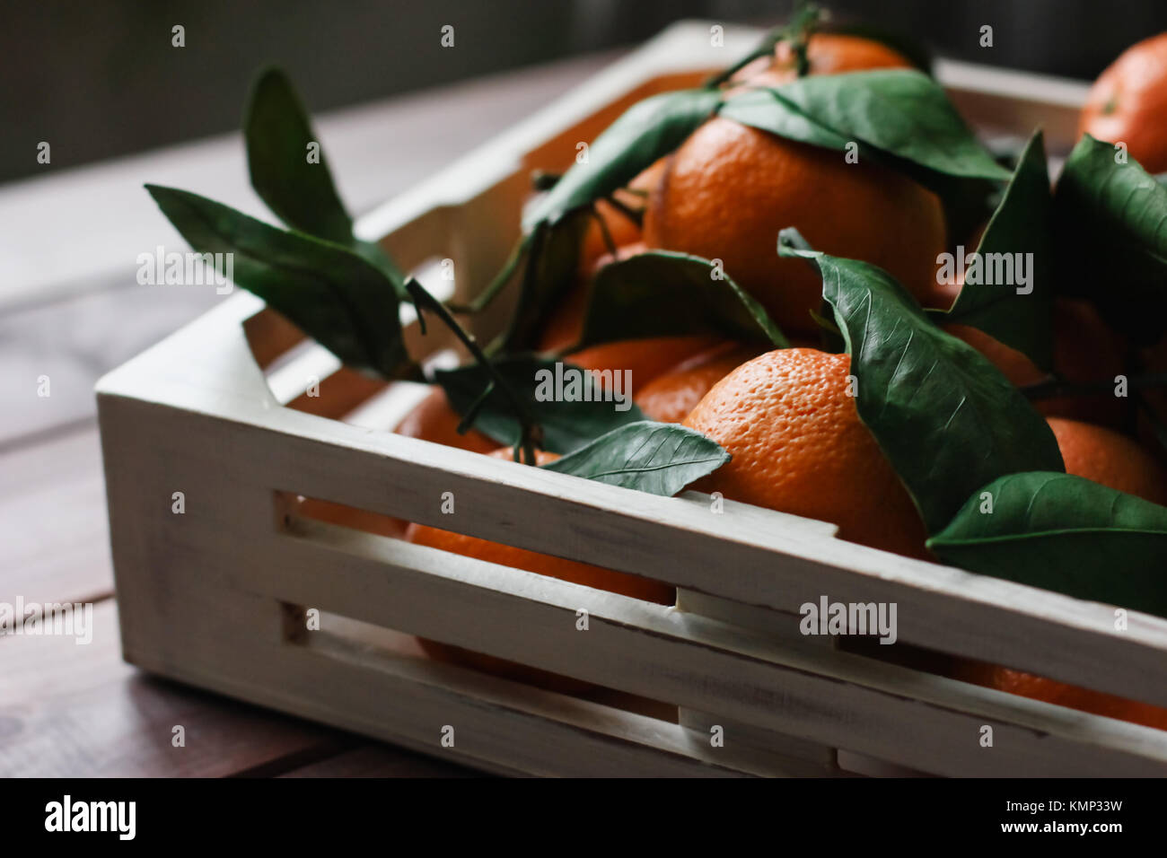 Holzkiste für frische Mandarinen mit Blättern auf dem Tisch Stockfoto