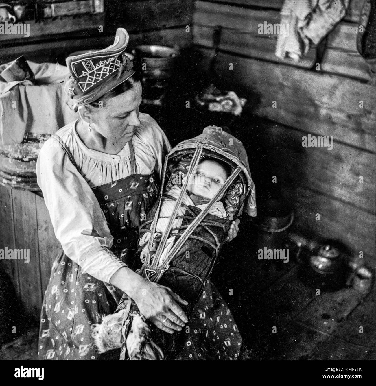 Winter Dorf. Skolt Sami Frau und ihrem Kind. Die Mutter trägt eine Perle bestickt hamtshik "Finnland Stockfoto