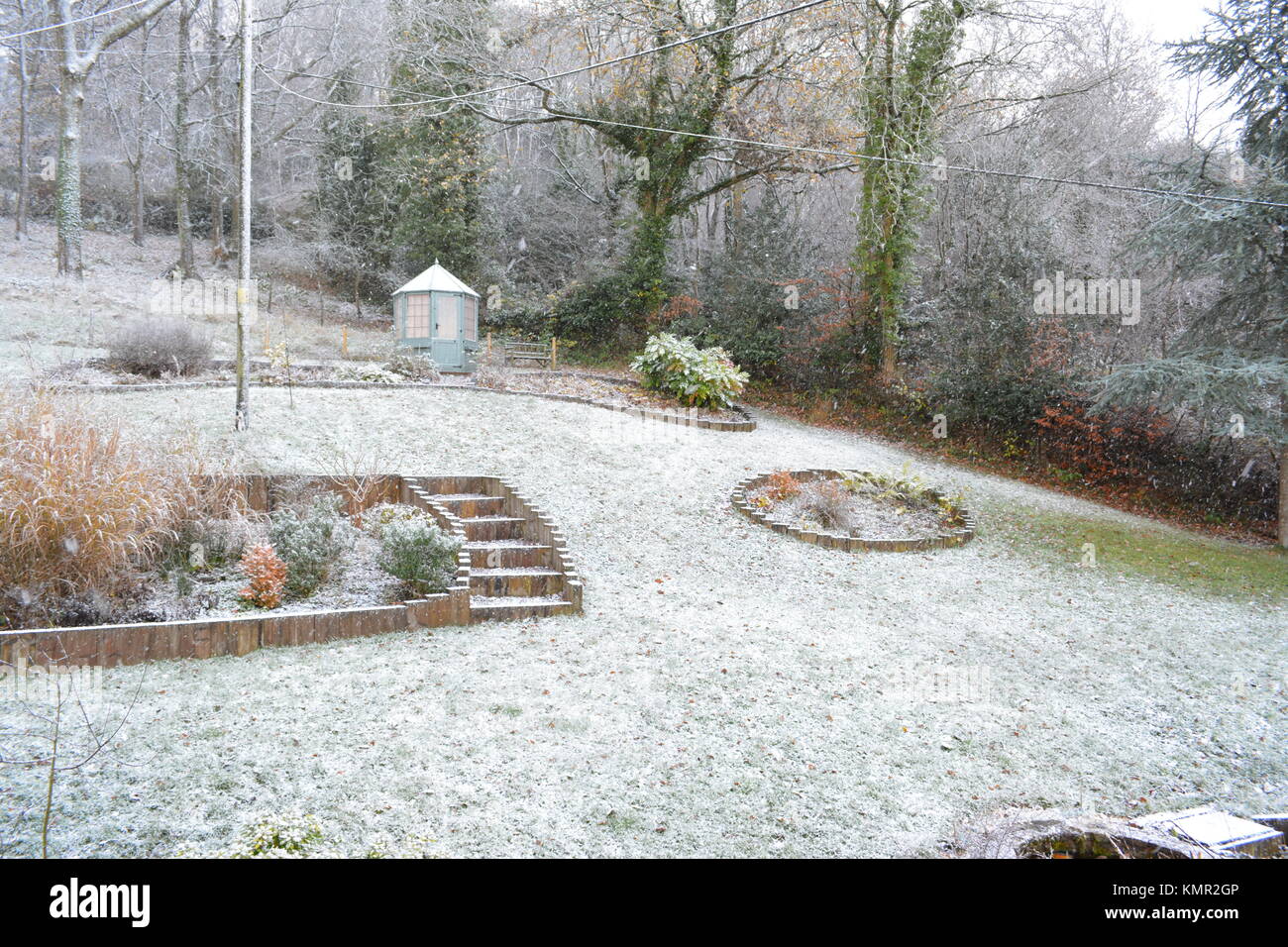 Großen abfallenden Garten mit Gartenhaus im Winter mit einer leichten Schneedecke auf dem Rasen Sträucher Bäume Sträucher und Betten in South herefordshire England Großbritannien Stockfoto