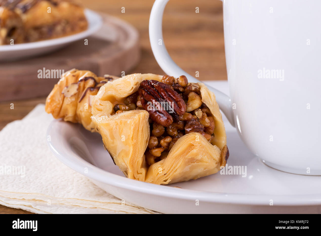 Nahaufnahme von Baklava auf einem weißen Teller mit Kaffeetasse Stockfoto