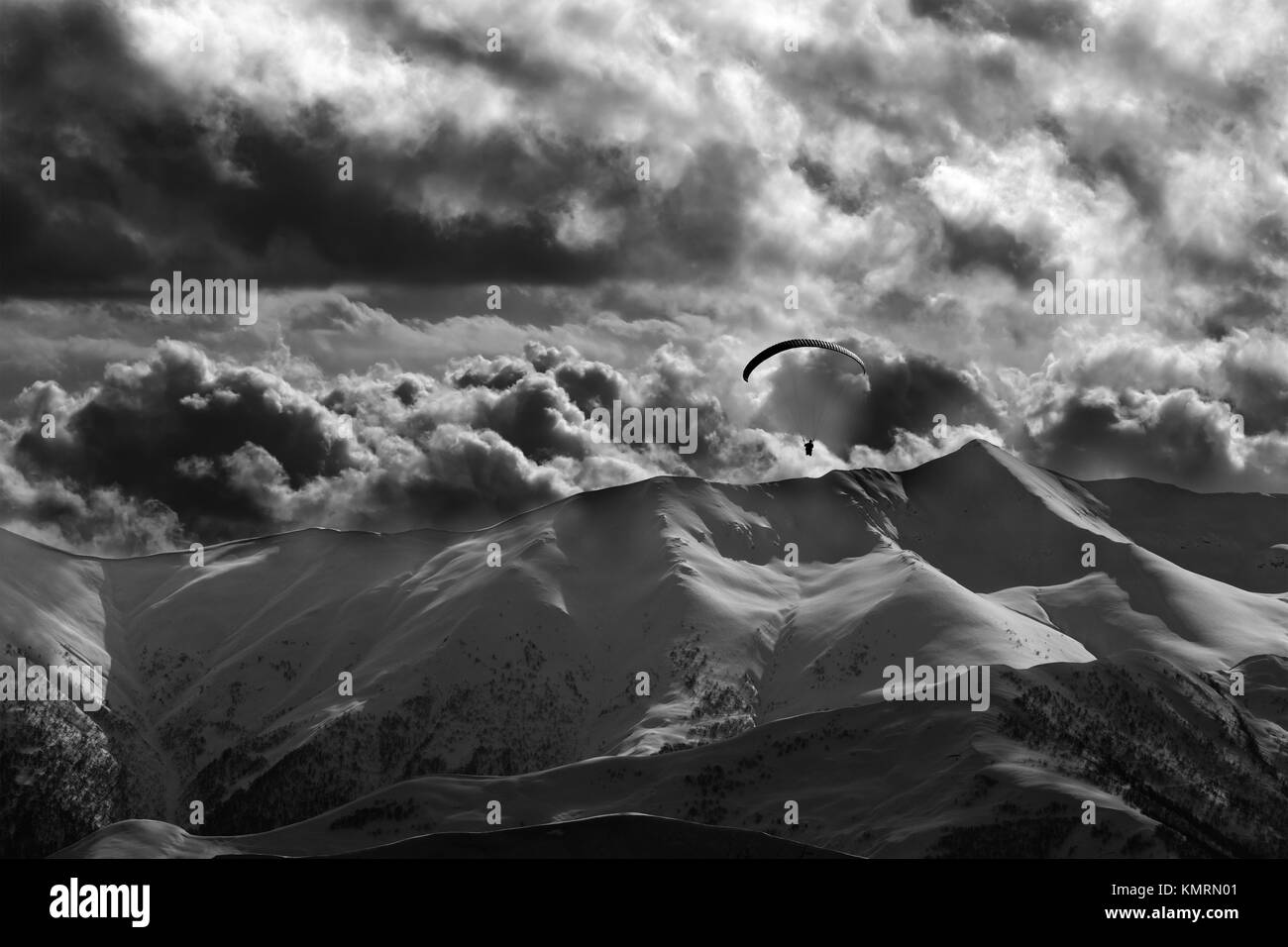 Abend Berg mit Wolken und Silhouette der Fallschirmspringer. Kaukasus Berge. Georgien, Region Gudauri. Schwarz und Weiß getönten Landschaft. Stockfoto