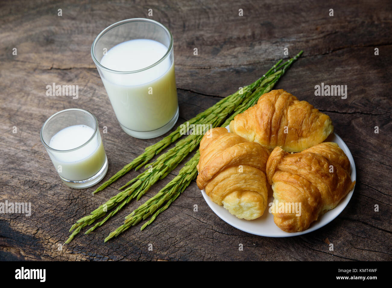 Croissant auf Teller mit Reis Milch und Ohr des Reises auf alten hölzernen Tisch für das Frühstück. Stockfoto